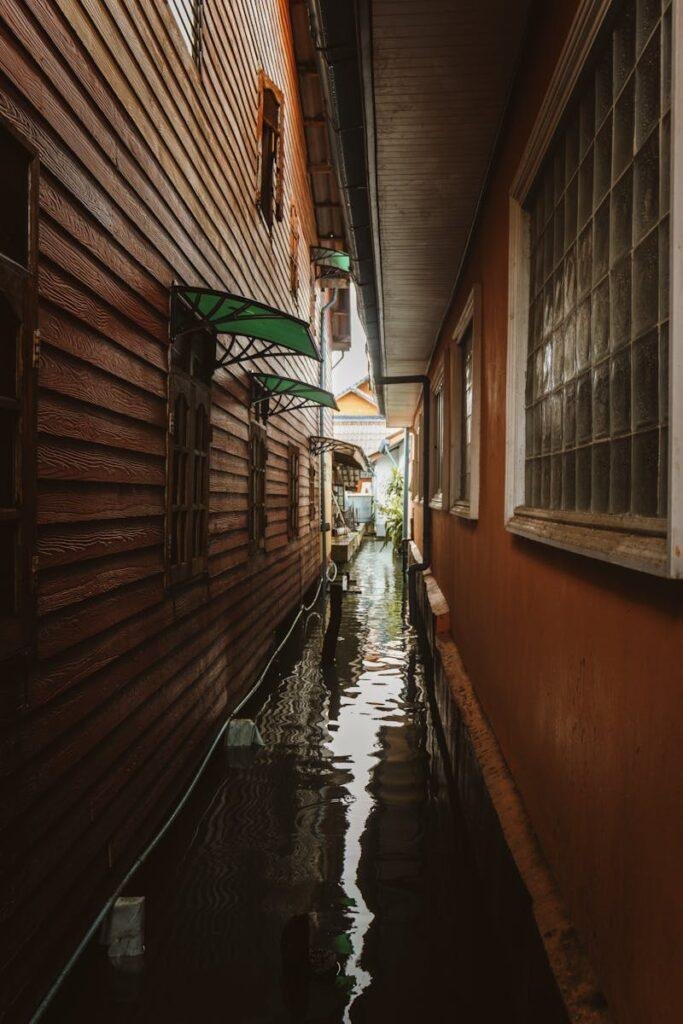 A narrow, flooded alleyway between wooden houses in Surat Thani, Thailand.